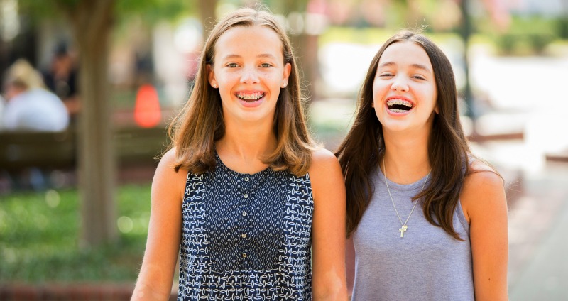 Two female teenagers with orthodontic braces smiling and laughing
