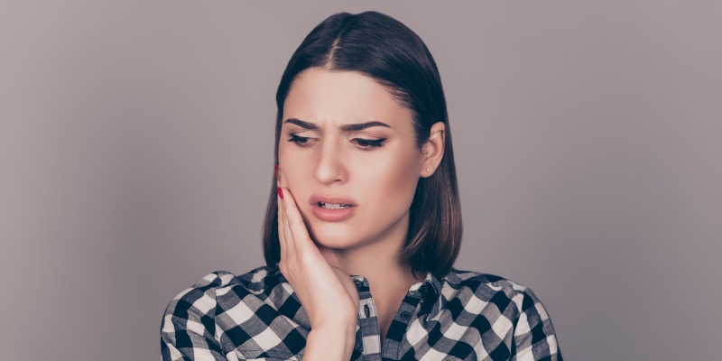 Girl holding her mouth in pain because of broken braces wire