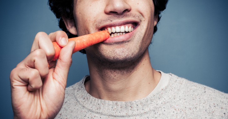 young male eating a carrot for healthy gums and teeth