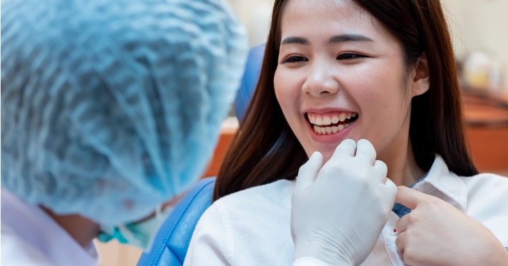 Dentist looking at patient's smile to determine use of retainers