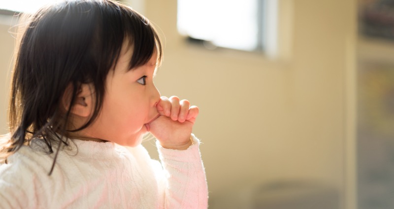 A young toddler sucking her thumb