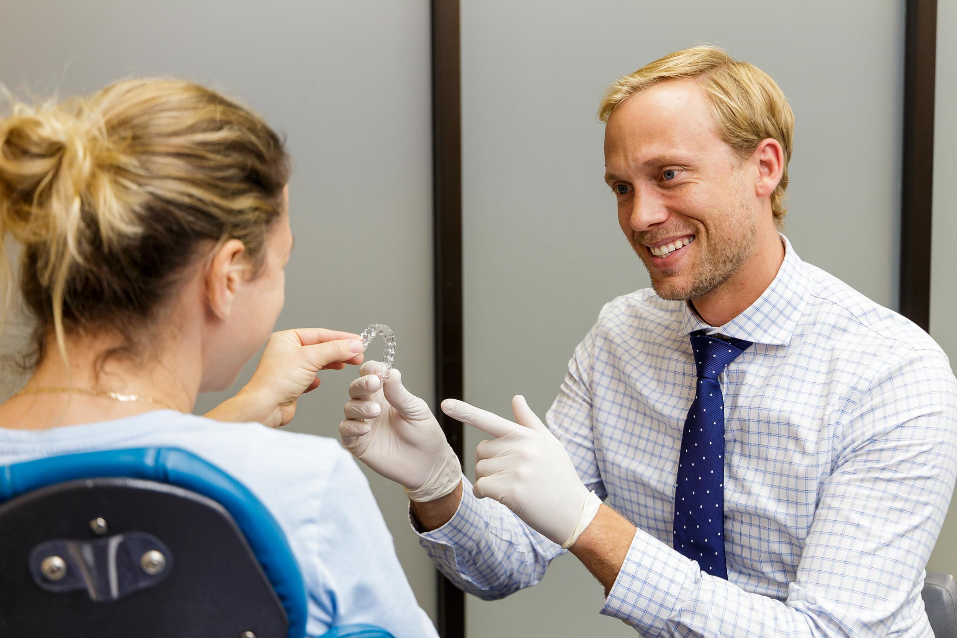 An orthodontist showing a patient their Invisalign clear retainer