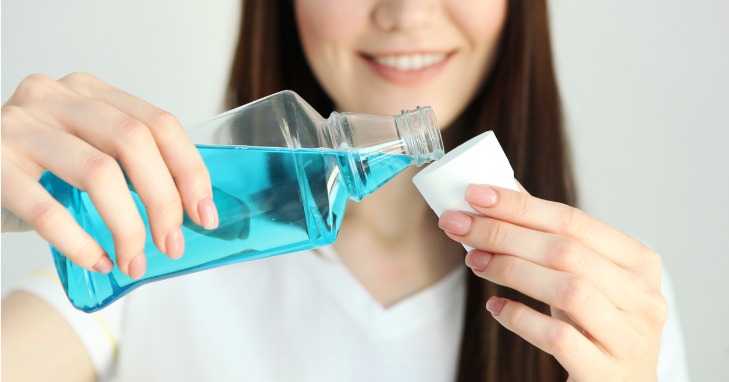 teenage girl pouring mouthwash into a small cup to use 