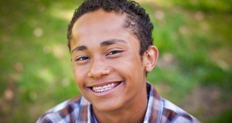 A young boy with orthodontic braces smiling 