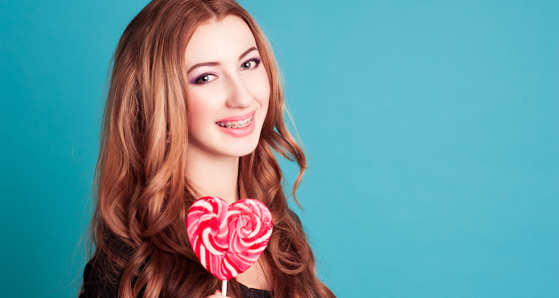 girl with braces holding a lolly
