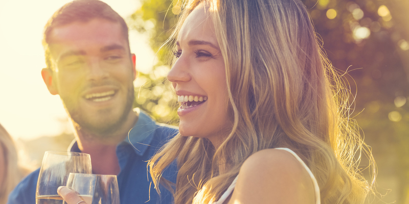 Happy couple driving wine. Both have straight teeth.