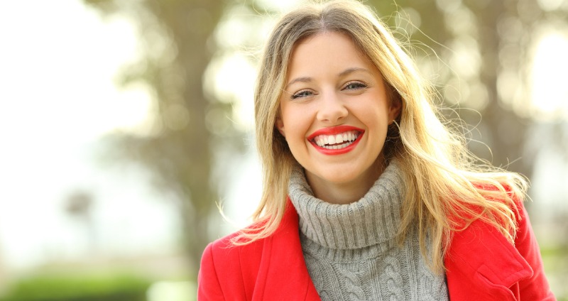 A woman in a park smiling showing off her straight teeth