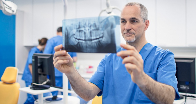 Male Orthodontist holding an x-ray of a mouth