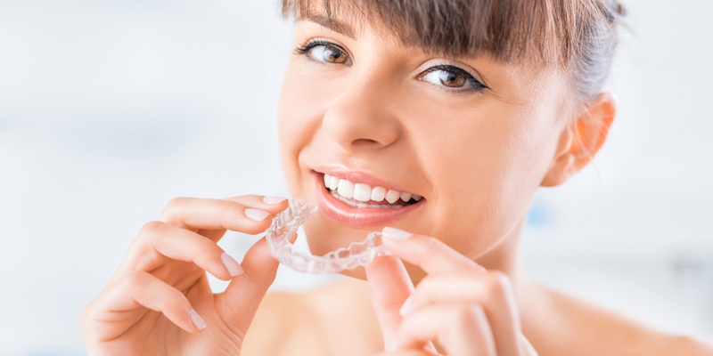 young woman holding an invisalign aligner