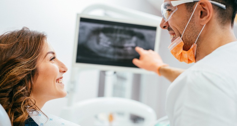 Orthodontist applying braces to young female patient 