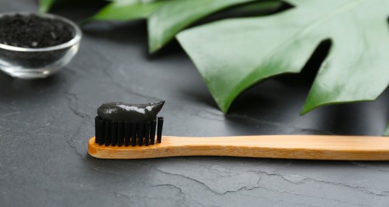 Toothbrush with activated charcoal toothpaste on it.