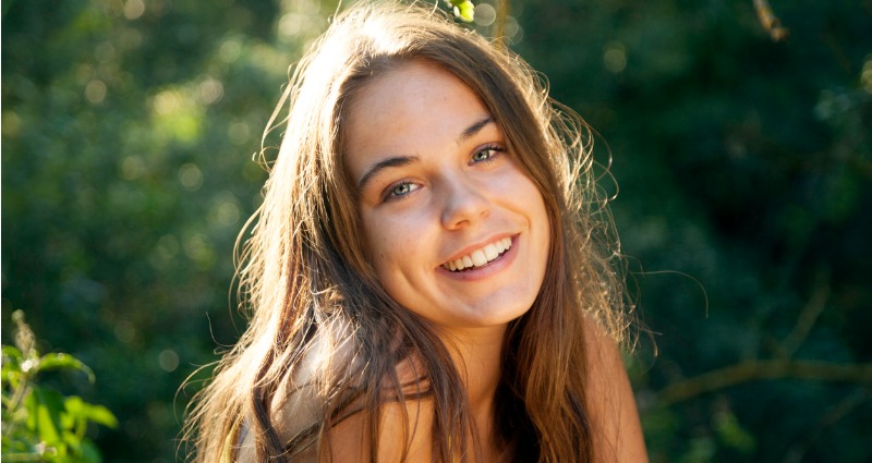 Young female smiling after her tooth gap was closed with braces 