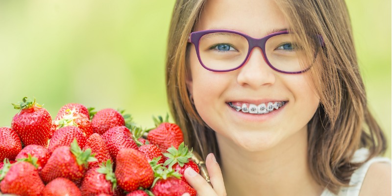 girl with braces eating a big bowl of strawberries