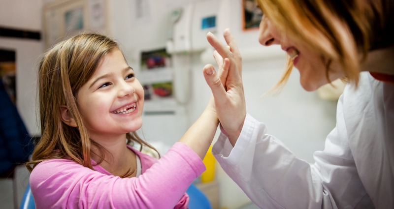 Young girl high fiving her orthodontist, while she explains different orthodontic terminology