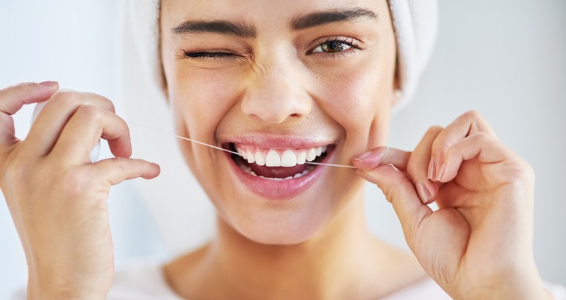 Young female patient flossing after having her braces removed 