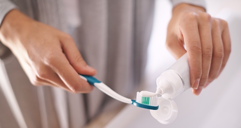 A woman putting fluoridated toothpaste on her toothbrush before brushing her teeth.
