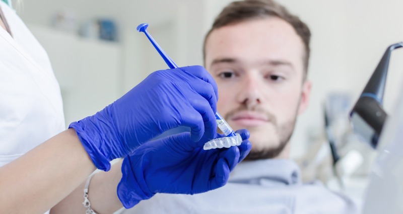  Young man getting his teeth whitened after having his braces removed. 