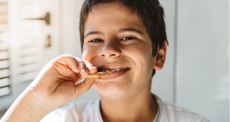 Young boy with braces eating breakfast and smiling. 