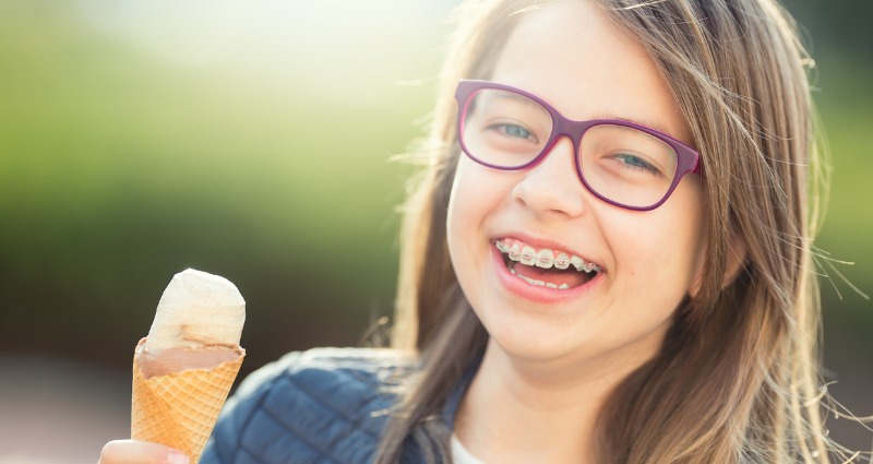 Young girl with braces eating a cold ice-cream