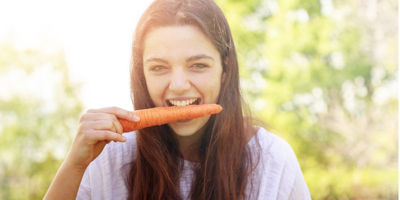 Woman eating a carrot, risking breaking her braces